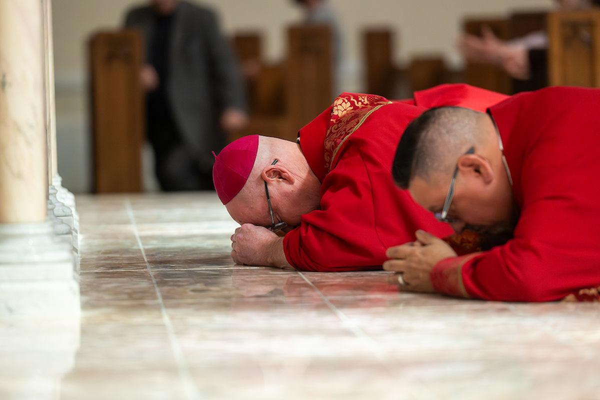 Un obispo y otros clérigos yacen rostro en tierra en oración sobre el suelo de mármol durante la liturgia del Viernes Santo.