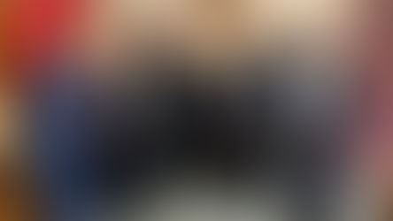 Seis sacerdotes y un hombre de traje posan sonrientes en una oficina con libros rojos y cuadros religiosos.