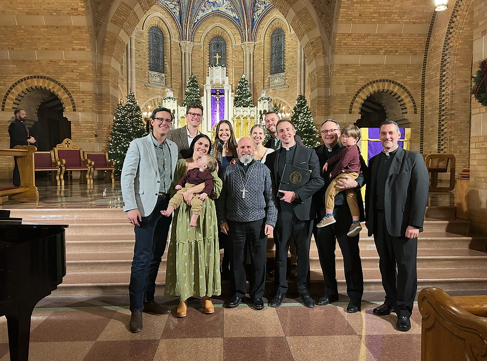 Will Ives sonríe para una foto con el arzobispo y amigos después de un concierto navideño.