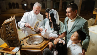 Bautizo en iglesia: sacerdote vierte agua sobre un bebé mientras la madre, el padre y niños observan con emoción.