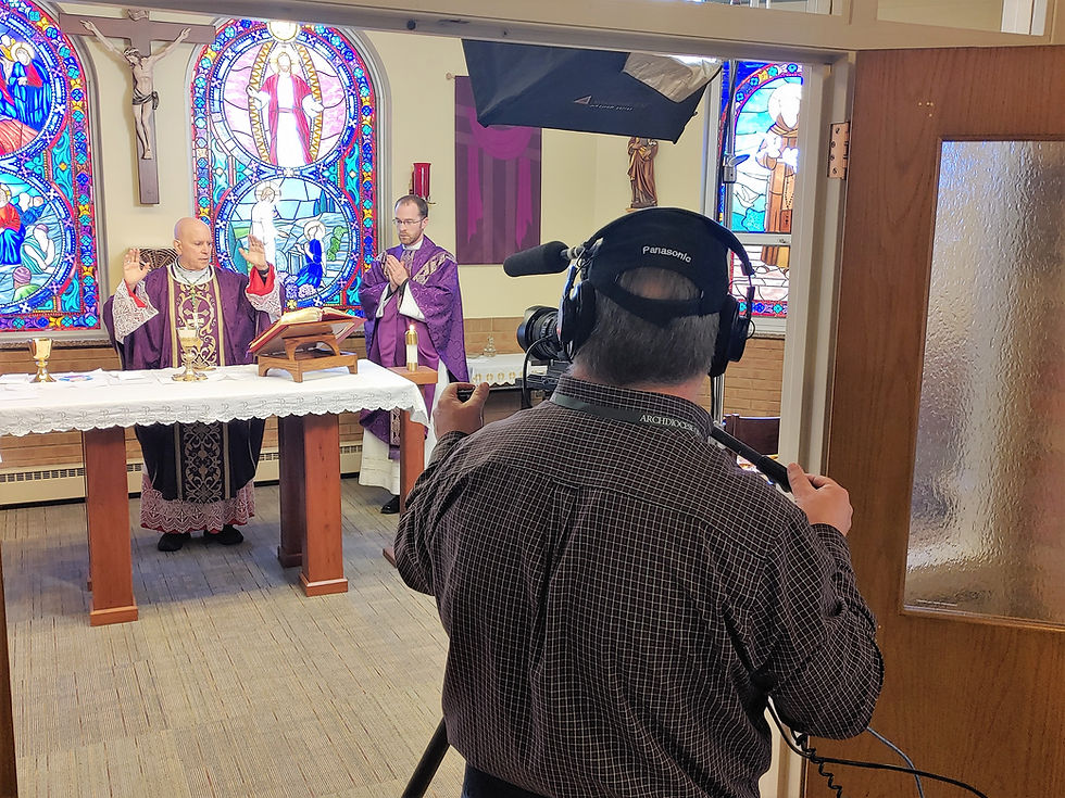 Sacerdotes con vestimentas púrpuras ofician misa frente a altar con vitrales coloridos. Un camarógrafo graba la escena en un ambiente solemne.