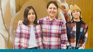 Tres personas sonríen frente a decoración de reno. Visten camisas a cuadros. Fondo de madera. Texto: "Appeal in Action" en la parte inferior.
