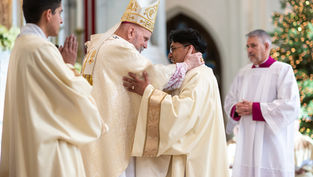 Obispo y sacerdote abrazándose en una ceremonia religiosa. Fondo de iglesia decorada, vestimenta blanca y dorada. Atmosfera solemne.
