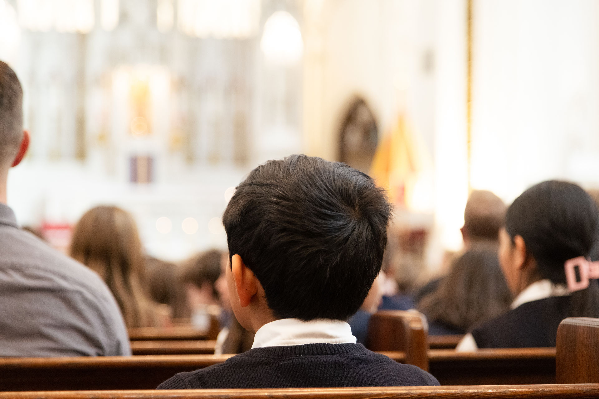 Personas sentadas en una iglesia, vista desde atrás. Ambiente iluminado con luz cálida. Sin texto visible. Ambiente tranquilo.