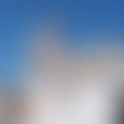El papa sonriente saluda desde un vehículo blanco en la Plaza de San Pedro, con la basílica al fondo y cielo azul.