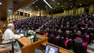El papa León habla ante una gran asamblea de obispos con sotanas negras y detalles fucsia en un auditorio solemne.