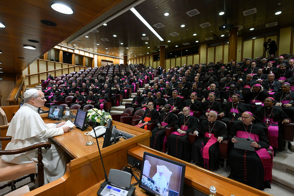 El papa León habla ante una gran asamblea de obispos con sotanas negras y detalles fucsia en un auditorio solemne.