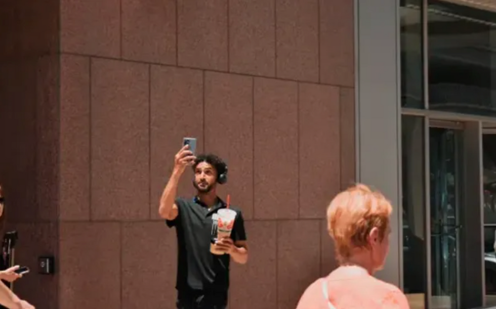 Un espectador toma una foto de la procesión eucarística en el centro de Denver el 9 de junio de 2024. Crédito: Kate Quiñones/CNA