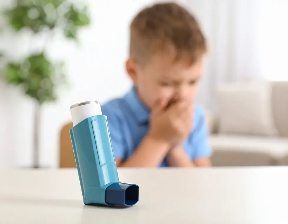 Inhalador azul en primer plano y niño borroso tosiento detrás, en una sala luminosa con plantas y sofá.