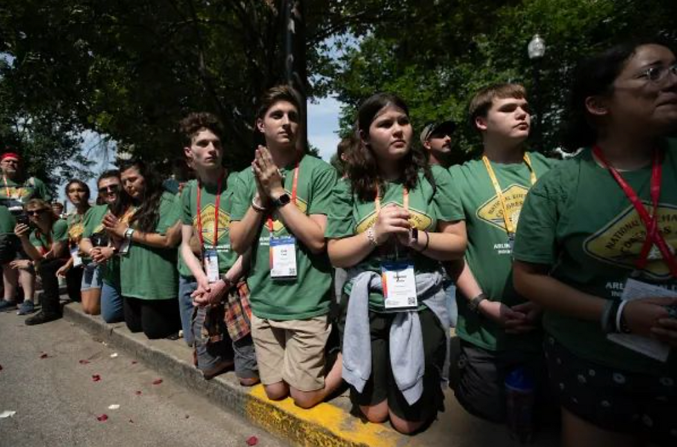 Jóvenes de rodillas en la procesión eucarística en Indianápolis. Crédito: Jeffrey Bruno