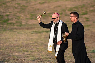 El arzobispo Samuel Aquila (izquierda) y el padre Jason Wunsch bendicen el terreno durante una cerem