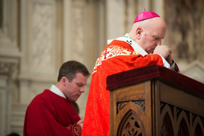 El arzobispo Samuel J. Aquila reza durante el servicio del Viernes Santo del 2015. (Foto de Daniel Petty)