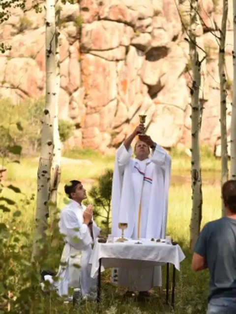 El padre Jason Wallace, director vocacional de la arquidiócesis, celebra la Misa durante un campamento del seminario.