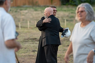 El padre Jason Wunsch (derecha) abraza al arzobispo Samuel Aquila (izquierda) durante una ceremonia 